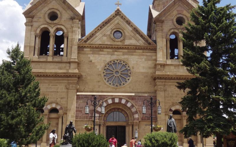 The entrance to the cathedral is flanked by statues of St. Francis on the left and Bishop Lamy on the right.