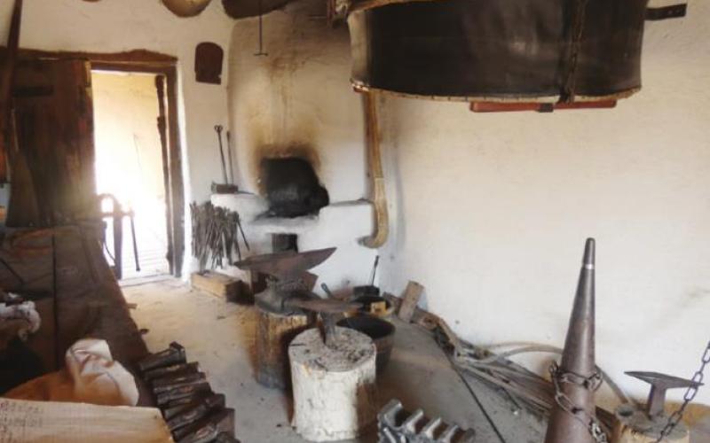 That black disk is the bellows used to fan the flames in the blacksmith’s forge.