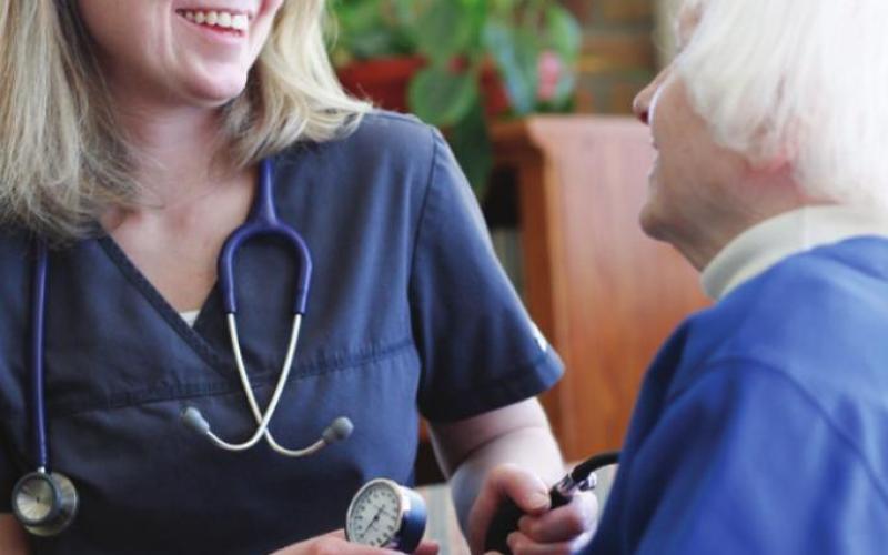 Jennifer, an Elizabeth Scott staff member, checks a resident’s blood pressure (photo taken before the onset of the pandemic).