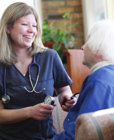 Jennifer, an Elizabeth Scott staff member, checks a resident’s blood pressure (photo taken before the onset of the pandemic).